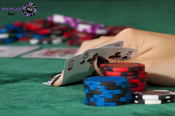 Poker player holding 5♣ 2♥ and chip stack, preparing to bluff